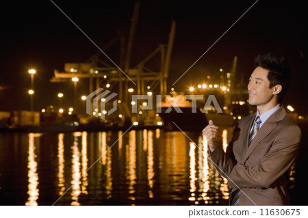 Asian businessman next to water at night Asian businessman next to water at night 11630675