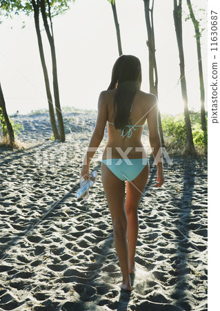 African woman walking on beach with trees African woman walking on beach with trees 11630687