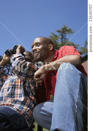 African father and son using binoculars 11630707