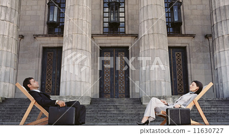 Businesspeople in lounge chairs in front of building Businesspeople in lounge chairs in front of building 11630727