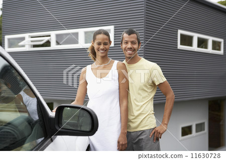 Multi-ethnic couple standing next to car 11630728