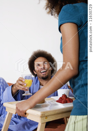 African woman bringing breakfast in bed to husband 11630729