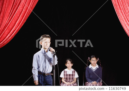 Asian boy speaking into microphone on stage Asian boy speaking into microphone on stage 11630749