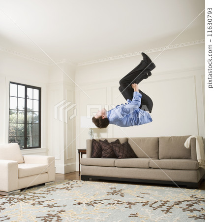 Hispanic businessman doing flip in livingroom Hispanic businessman doing flip in livingroom 11630793