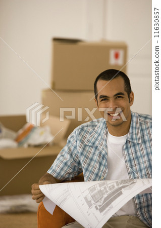 Young man looking at blueprints in new house 11630857