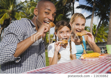 Mixed Race family eating at picnic table 11630862