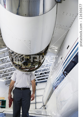 Repairman standing behind airplane engine 11630877
