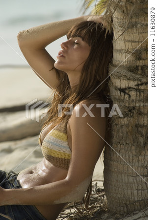 Young woman leaning against tree 11630879