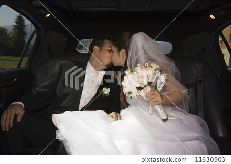 Hispanic newlyweds kissing in limousine 11630903