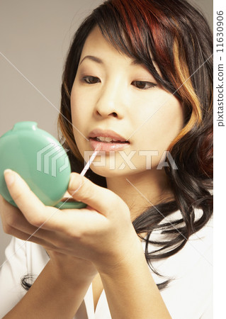 Asian woman applying lip gloss 11630906