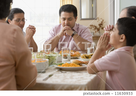 Hispanic family praying at dinner table Hispanic family praying at dinner table 11630933