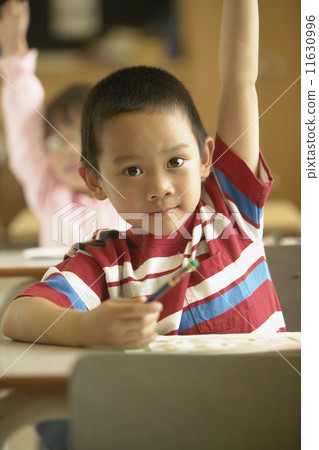Young boy raising hand in classroom 11630996