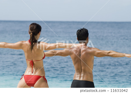 Multi-ethnic couple practicing yoga at beach 11631042