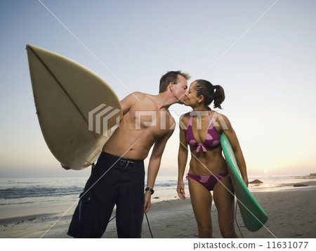Multi-ethnic surfer couple kissing 11631077