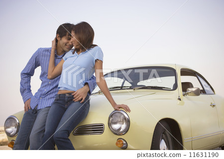 Couple embracing on hood of car 11631190
