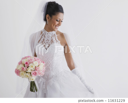 Hispanic bride holding bouquet 11631229