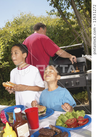 Boys eating hamburgers at backyard barbecue Boys eating hamburgers at backyard barbecue 11631272