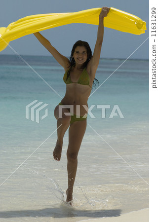 Hispanic woman jumping on beach 11631299