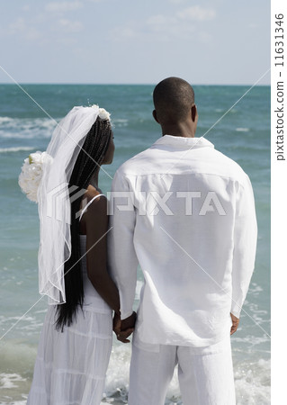 African bride and groom holding hands at beach African bride and groom holding hands at beach 11631346