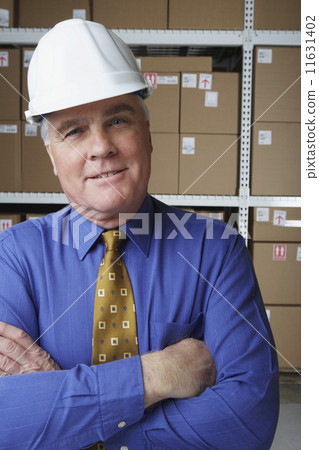 Businessman wearing hard hat in warehouse 11631402