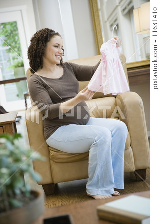 Pregnant African woman looking at baby clothes 11631410