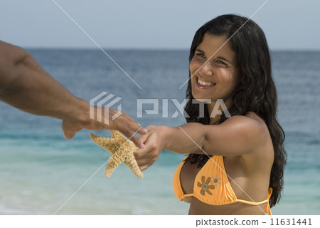 Hispanic woman handing starfish to boyfriend Hispanic woman handing starfish to boyfriend 11631441