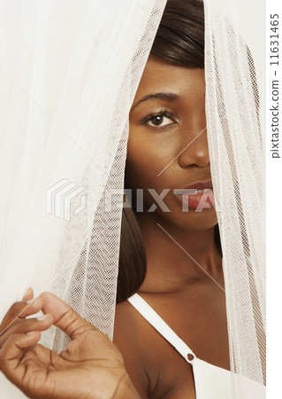 African woman looking through curtains 11631465