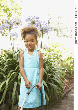 Mixed Race girl holding garden hose Mixed Race girl holding garden hose 11631488