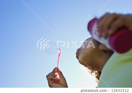 Low angle view of girl blowing bubbles 11631512