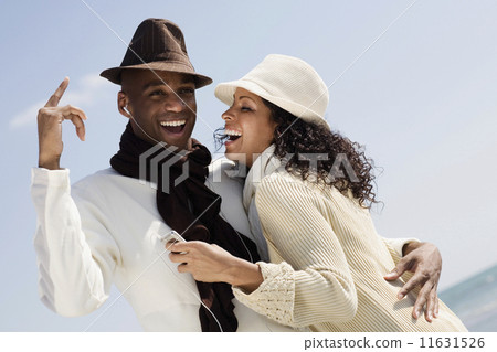 Multi-ethnic couple listening to mp3 same player 11631526