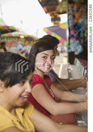 Multi-ethnic teenaged friends playing carnival game Multi-ethnic teenaged friends playing carnival game 11631540