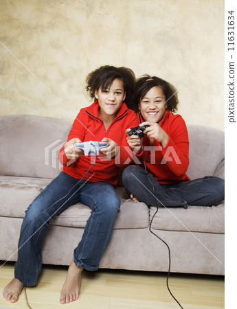 African twin sisters playing video games 11631634