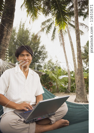 Asian man with laptop in hammock 11631671