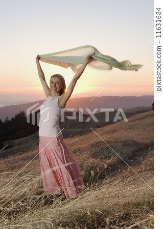 Senior woman holding her sweater into the wind Senior woman holding her sweater into the wind 11631684