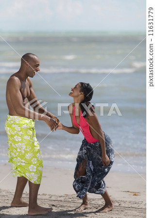 Multi-ethnic couple holding hands at beach Multi-ethnic couple holding hands at beach 11631779