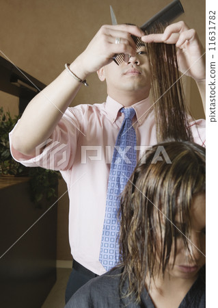 Asian male hairstylist cutting hair 11631782