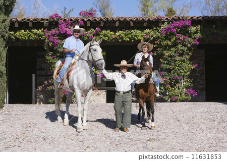 Hispanic man leading couple on horses 11631853