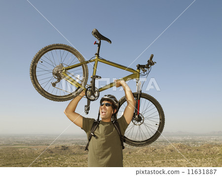 Hispanic man holding bicycle over head Hispanic man holding bicycle over head 11631887