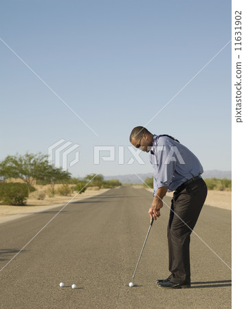 African businessman playing golf in road 11631902