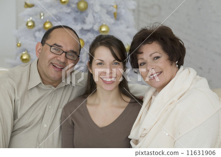Hispanic parents and adult daughter next to Christmas tree Hispanic parents and adult daughter next to Christmas tree 11631906