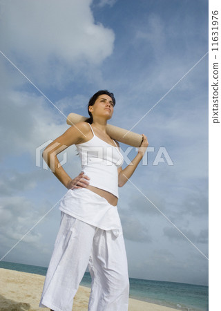 Woman holding yoga mat at beach 11631976