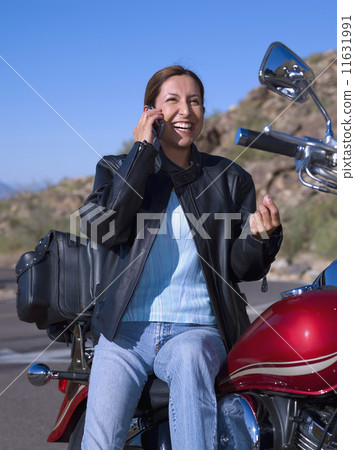 Hispanic woman on motorcycle talking on cell phone Hispanic woman on motorcycle talking on cell phone 11631991