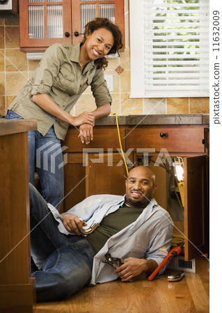 African couple installing kitchen sink 11632009