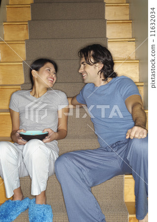 Multi-ethnic couple smiling at each other on stairs 11632034