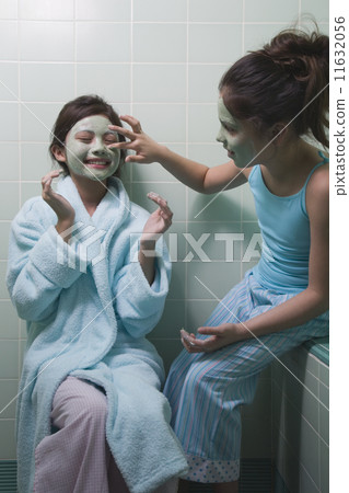 Two young girls applying facial masks in bathroom 11632056