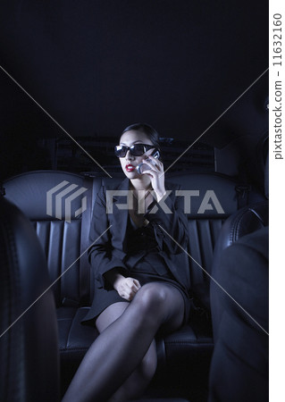 Asian businesswoman using cell phone in back seat of car 11632160