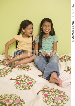 Pacific Islander sisters listening to mp3 player 11632162