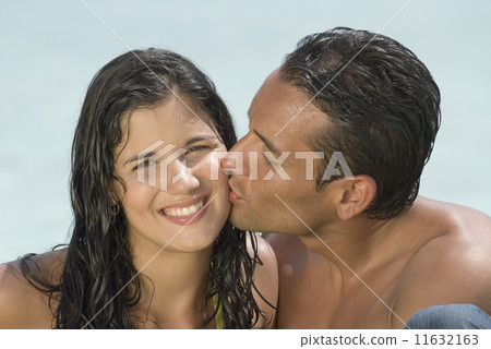 Hispanic man kissing girlfriend on cheek 11632163