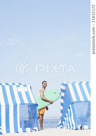 Hispanic man holding boogie board at beach Hispanic man holding boogie board at beach 11632172