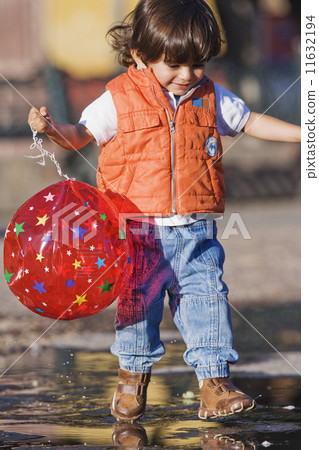 Hispanic boy walking in puddle 11632194
